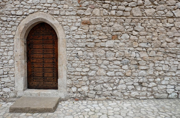 wooden back door in white / gray stone wall