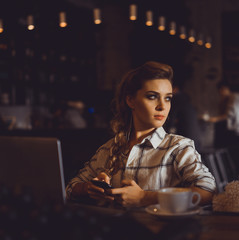 young pretty brunette woman eat chocolate in cafe, using smartphone and laptop touch screen display, sweet food, tasty breakfast, close up portrait, hipster girl, fanny, drink coffee