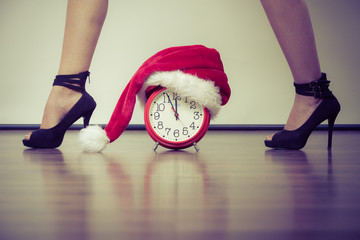 Woman in high heels with alarm clock. Christmas.