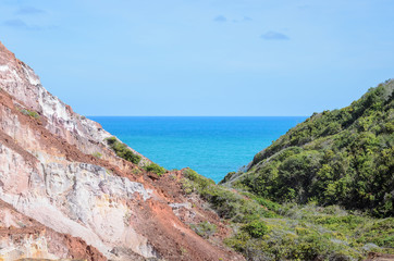 Canyon of cliffs with many stones sedimented by time, rocks with red and yellow colors and the sea in the background. Cliffs of Coqueirinho beach, PB - Brazil.