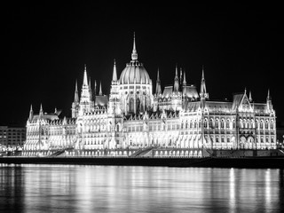 Naklejka premium Night view of illuminated historical building of Hungarian Parliament, aka Orszaghaz, with typical symmetrical architecture and central dome on Danube River embankment in Budapest, Hungary, Europe. It