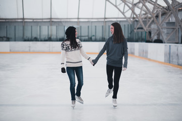 Obraz premium Friends on skates at ice-skating rink skating together.