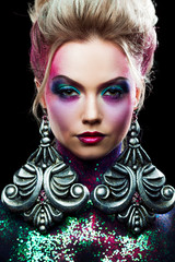 Young attractive blonde girl in bright art-makeup, high hair, body painting. Rhinestones and glitter