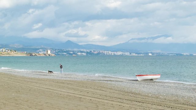 Man with Dogs on Mediterranean Beach in Southern Spain at Manilva with Estepona City in the Background