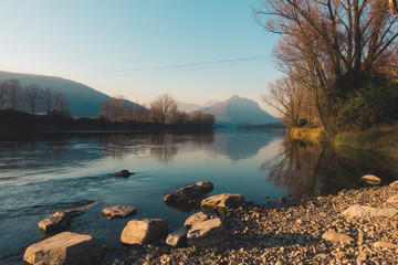 View of river and with vegetation stones and mountains in the background in autumn