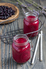 Black currant, greek yogurt, honey and lavender smoothie in glass jar with berries and flowers on background, vertical