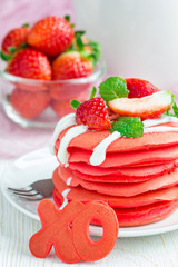 Stack of red velvet pancakes with xo sign (hugs and kisses) on white plate, vertical