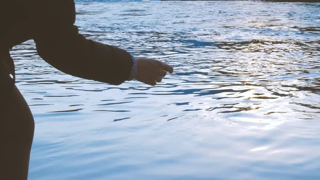 Throwing stones in a pond at sunset