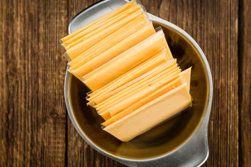Portion of Cheese slices on wooden background (selective focus)