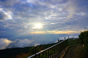 Mountain landscape with wave of fog, cloudy sky and metal fence