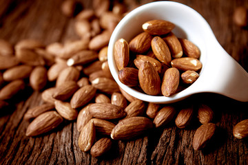 close up Peeled almonds nut  in small white cup on wood