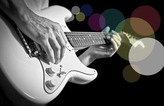 musician hands playing electric guitar, bw filter & colorful bokeh