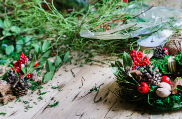 women make traditional christmas door wreath with moss and berry
