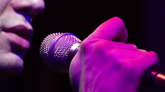 Close up of mouth of the male singer performs song in microphone on concert
