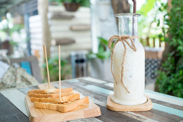 Breakfast . Iced fresh milk and Bread, butter beans . Placed on a wooden table ready to serve you for holidays . Customize colors Vintage retro and old film Tone . Coffee break