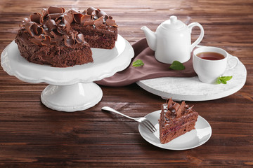 Delicious chocolate cake with tea on table