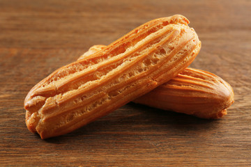 Delicious eclairs on wooden background