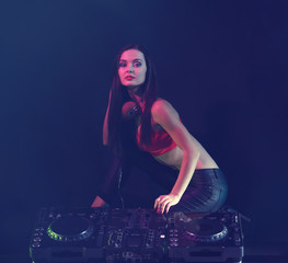 Pretty young woman with DJ console on dark background