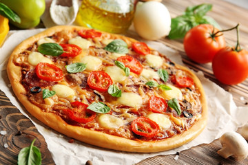 Fresh pizza with tomatoes, cheese and mushrooms on wooden table closeup