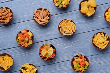 Fototapeta premium Different kinds of pasta in bowls on wooden background