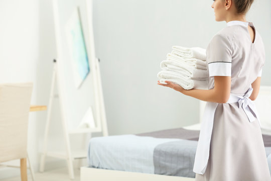 Chambermaid holding pile of clean towels in the room