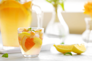 Fototapeta premium Refreshing citrus infused water with lemon, orange, and mint in a glass on a white table