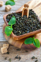 Wooden bowl of dry green tea and melissa leaves.