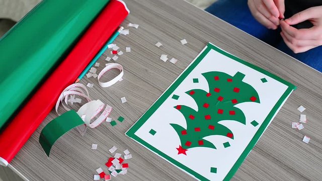 Teen making Christmas card from colored self-adhesive papers