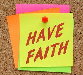 The words Have Faith in red text on a yellow sticky note pinned to a cork notice board