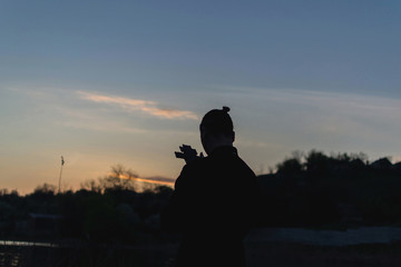 Young priest shot from back holding a crucifixion in hands and looking at it