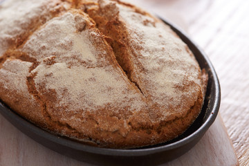 soda bread  on a oval cast iron pan over a wooden table