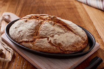 Naklejka premium soda bread on a oval cast iron pan over a wooden table