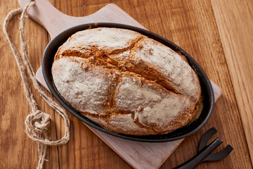 soda bread  on a oval cast iron pan over a wooden table