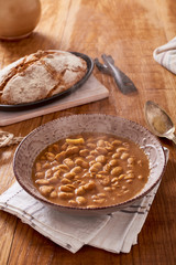 soda bread  on a oval cast iron pan and bean soup over a wooden table