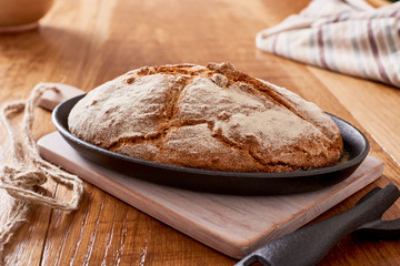 soda bread  on a oval cast iron pan over a wooden table