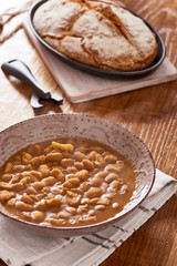 soda bread  on a oval cast iron pan and bean soup over a wooden table