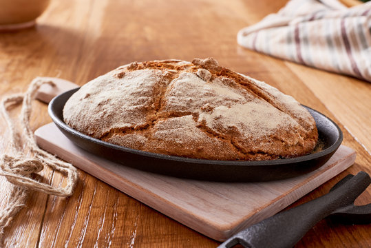 Soda Bread  On A Oval Cast Iron Pan Over A Wooden Table