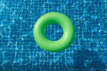 Green pool float, ring floating in a refreshing blue swimming pool