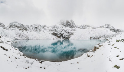 panorama of incredible blue lake surrounded by a chain of high snow-capped mountains
