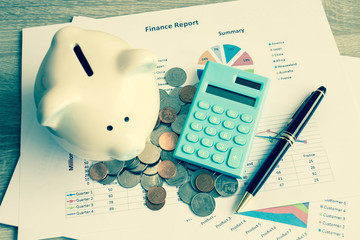 Piggy bank with calculator on wood table, business and finance concept, vintage color tone.