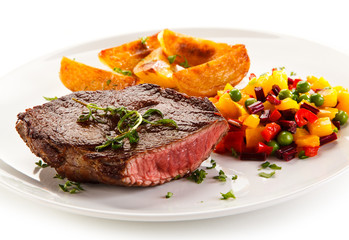 Grilled steak, baked potatoes and vegetable salad on white background 