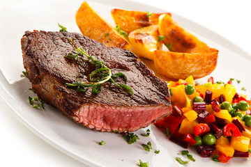Grilled steak, baked potatoes and vegetable salad on white background 