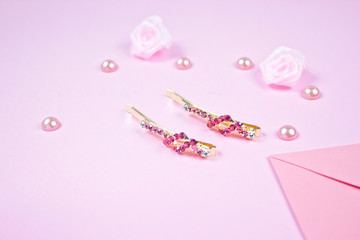 Golden hairpins with pink gemstone and pink ribbon on pink background