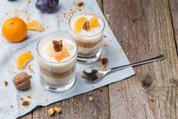 Fresh homemade dessert with biscuits, yogurt, tangerines and walnuts, served in a glass