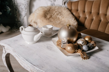 Christmas decorations on the table against the background of a fireplace decorated with branches spruce and garland.