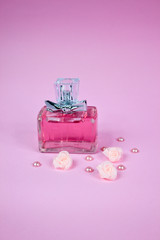 Pink aromatic perfume with pink pearls and pink roses on pink background