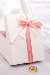 White gift box with red bow over white satin