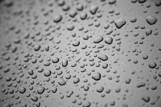 Rain drops on black and white metal surface.