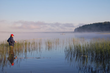 The fisherman stands in the water and catch fish on fishing rod