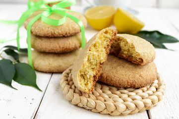 Shortbread lemon flavored cookies: a broken and connected green ribbon for a gift. Fresh lemon on a white wooden background. Close up